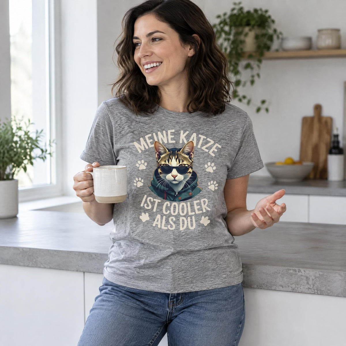 Woman wearing a cotton t-shirt with a cat graphic print while standing in a modern minimalist kitchen.